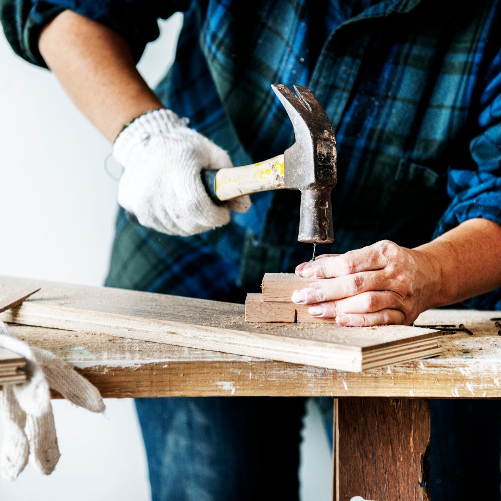 Woman carpenter using hammer pushing nail on a wood